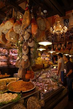 people are shopping in an open market with lots of food on the shelves and hanging lights