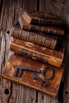 an old key and some books sitting on top of a wooden table next to each other