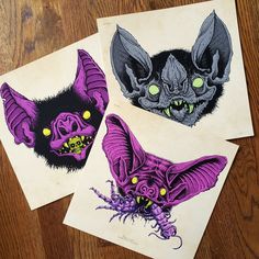 two pictures of bats with yellow eyes on them sitting on a wooden table next to each other