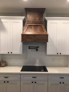 a stove top oven sitting inside of a kitchen next to white cupboards and drawers