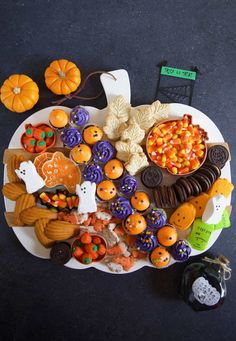 a white plate topped with lots of halloween cookies and candies on top of a table