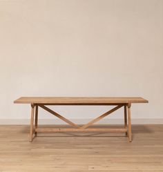 a wooden table sitting on top of a hard wood floor next to a white wall