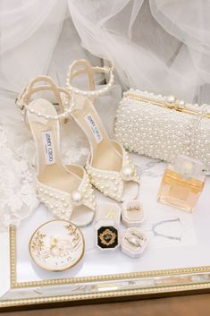 a table topped with white shoes and jewelry next to a purse on top of a table