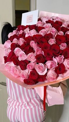 a woman holding a large bouquet of red and pink roses