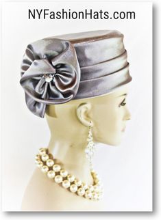 Women's Silver Gray Satin Couture Formal Pillbox Cocktail Wedding Church Hat. This Classic Styled Dressy Pillbox Holiday Hat Is Embellished With A Satin Bow Enhanced With A Rhinestone. This Bridal Mother Of The Bride Headpiece Can Be Worn With Embellishments Toward The Face Or To The Back Of The Head. This Elegant Satin Pillbox Hat Is Custom Made And Designed By NY Fashion Hats Couture Millinery. https://www.nyfashionhats.com. This New Collection Headpiece Is Part Of The Anastasia Konstandina Couture Headdress Line. This ladies bespoke pillbox hat is appropriate to wear for horse races, The Kentucky Derby, The Dubai World Cup, The Royal Ascot, The Melbourne Cup, Belmont Stakes, The Preakness Stakes horse racing, Church, weddings, and special occasion. This hat is also suited for mother of Mother Of The Bride Hats, Church Lady Hats, Bridal Fascinator, Church Hat, Bride Hat, Bridal Hat, Wedding Church, Bride Headpiece, Vintage Rhinestone Brooch