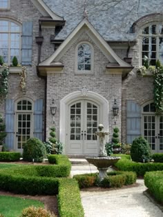 a large brick house with hedges around the front door and entry way leading to it