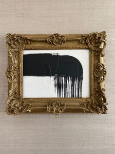 an ornate gold frame holds a black and white painting