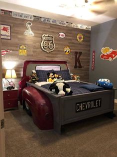 a child's bedroom decorated in gray and red with cars on the wall behind the bed