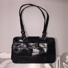 Genuine Semi-Shined Black Leather With Crocodile Embossed Texturing. Ornamental Silver Tone Hardware. Front Features A 3/4 Zip-Around Compartment And A Decorative Closure Flap With Magnet Snap Fastener. Back Features A Discreet, Flat, Zippered Pocket. Two Interior, Zippered, Privacy Pockets And A Bonus Key Ring Inside. Size H8"X W14" X B4". Shoulder Drop Is 12" Art. No. Sa 67615 -52-29 Handbag Patterns, Snap Fasteners, Key Ring, Zipper Pocket, Silver Tone, Black Leather, Bag Lady, Key, Zipper