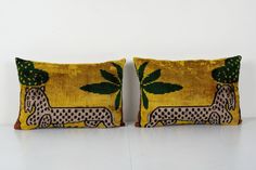 two decorative pillows with dogs on them, one is yellow and the other is green