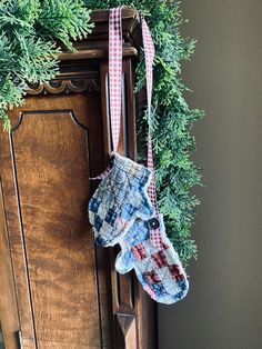 a pair of mitts hanging from a christmas wreath on an old wooden armoire