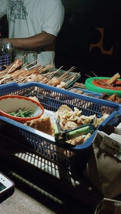 several trays of food sitting on top of a table next to a cell phone