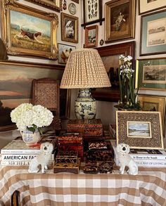 a table topped with books and pictures next to a lamp on top of a table