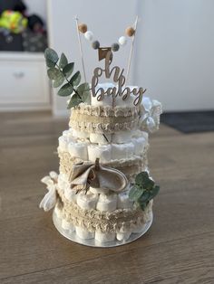 a three tiered cake decorated with baby's name and bows on top, sitting on a wooden table