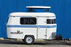 an old camper parked in front of a blue wall with the word merekat written on it