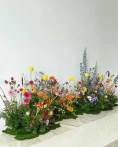 an arrangement of colorful flowers and greenery on display