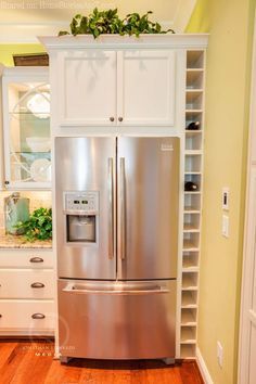 a stainless steel refrigerator freezer sitting inside of a kitchen next to white cupboards