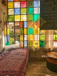 a bed sitting under a window covered in lots of colorful glass blocks next to a chalkboard