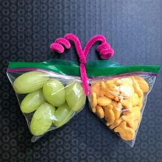 two bags filled with grapes and crackers sitting on top of a carpeted floor