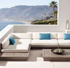 a white couch sitting on top of a wooden table next to a large open window