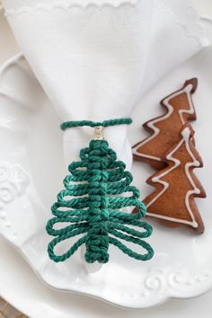 two small christmas trees are sitting on a white plate next to some cookies and napkins