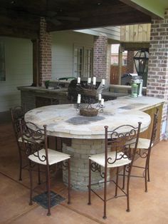 a table with chairs around it in the middle of an outdoor kitchen and dining area