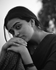 a black and white photo of a woman with her hand on her shoulder looking at the camera