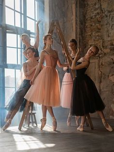 four young ballerinas in tulle skirts posing for a photo with their arms up