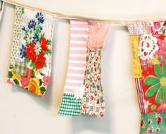 colorful fabric hanging from a clothes line with flowers and stripes on the clothes pegs