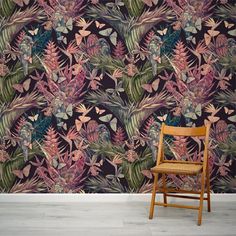 a wooden chair sitting in front of a wall with a floral pattern on the wall