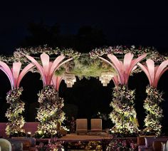 an outdoor wedding setup with pink flowers and greenery on the stage, surrounded by chairs