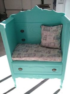 a blue bench with a pillow on top of it and some drawers in the back