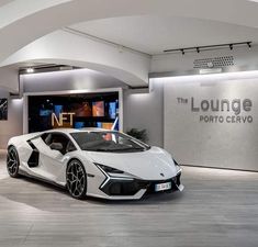 a white sports car is parked in front of a sign that says lounge porto cervo