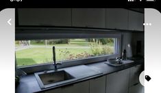 an image of a kitchen with a sink and window looking out on the yard outside