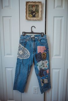 an old pair of jeans with patches hanging on a hook in front of a door