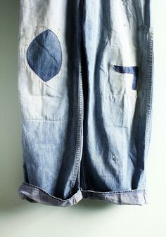 an old pair of blue jeans with holes on them hanging from a clothes line against a white wall