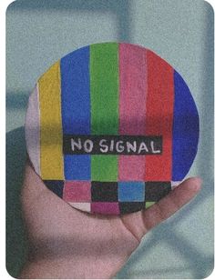 a person holding up a colorful sticker with the word no signal written on it