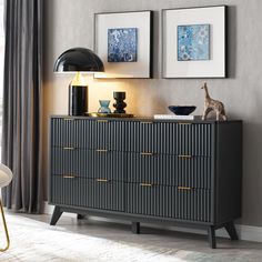 a black and gold dresser with two pictures on the wall