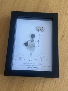 a framed paper art depicting a woman holding balloons with the number 80 on it's side