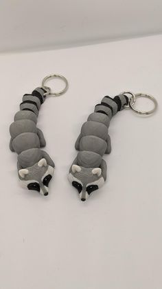 two key chains are shaped to look like a caterpillar, one is gray and the other is black