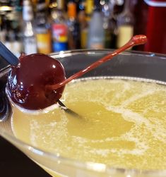 a spoon with some liquid on it and a cherry in the bowl next to it