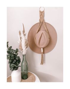 a hat hanging on the wall next to a vase