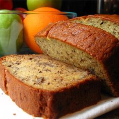 sliced loaf of banana bread next to apples and oranges