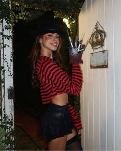 a woman wearing a black hat and red striped shirt is holding up her hand in the air