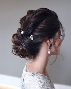 a woman with her hair up in a low bun and pearls on the top of her head