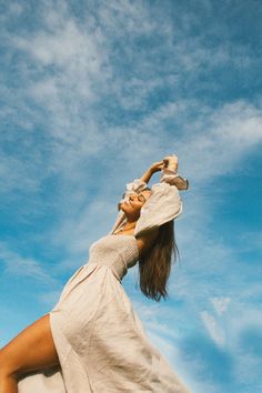 a woman in a white dress and hat is flying through the air with her hands on her head