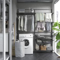 a washer and dryer in a room with clothes hanging on the rack next to it