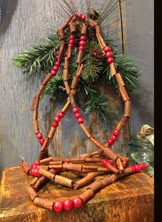 a christmas decoration made out of cinnamon sticks and red beads on top of a wooden table