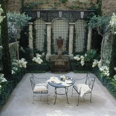 an outdoor dining area with tables and chairs in the foreground, surrounded by greenery