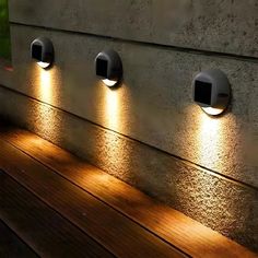 four lights are on the side of a wall with wood flooring and light reflecting off it's sides